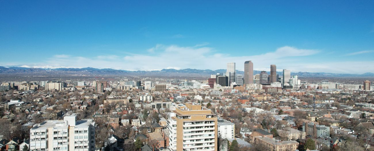 Aerial view of a downtown city with a mountain range and blue sky in the background